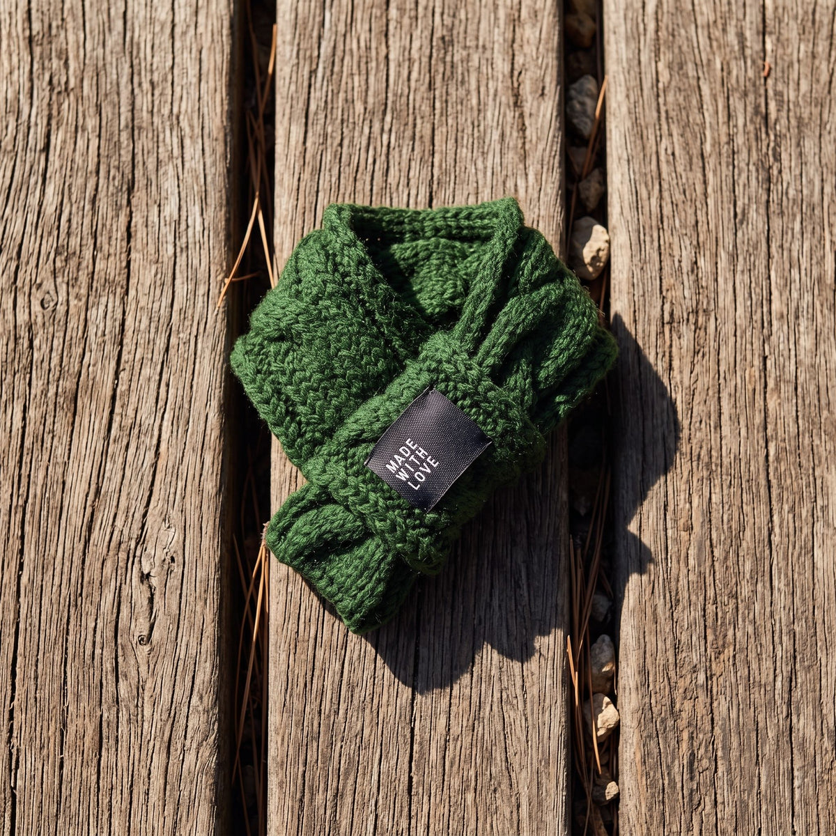 Close-up of thick cable-knit wool dog scarf styled on weathered oak surface, highlighting knit pattern and wool texture.