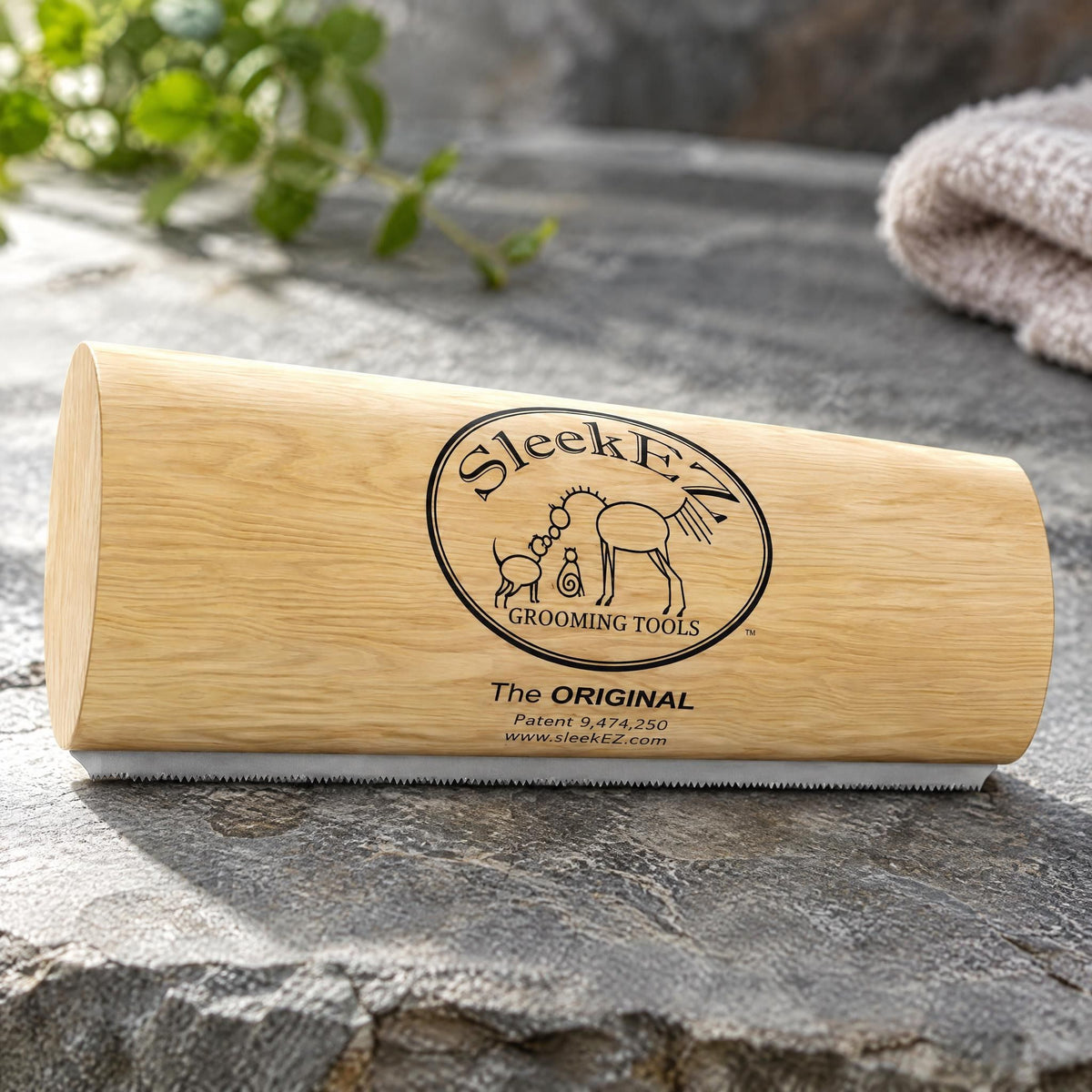 Deshedding grooming brush for dogs and cats with a wood-grain handle resting on a grey stone surface.