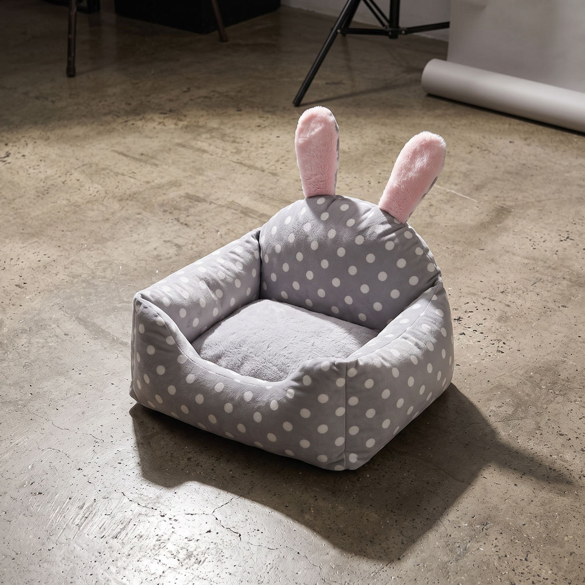 Dog bed positioned on a polished concrete floor in a studio, highlighting plush material and contrast with hard surface.
