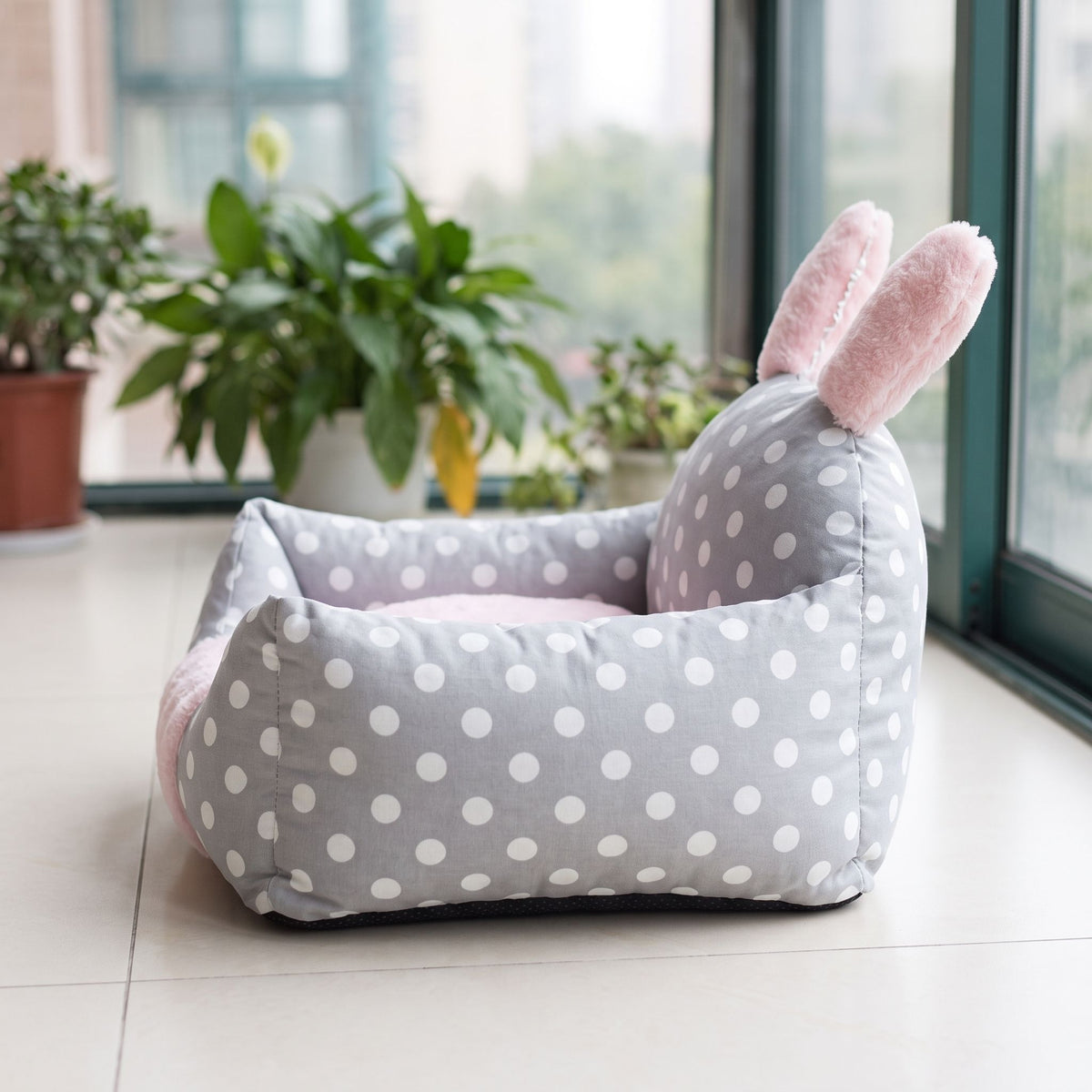 Side-profile of dog bed on white-tiled sunroom floor, illuminated by diffused daylight, focusing on backrest and cushioned interior.