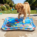 Full shot of colorful pet water mat on a concrete patio with a happy dog splashing in a backyard garden.