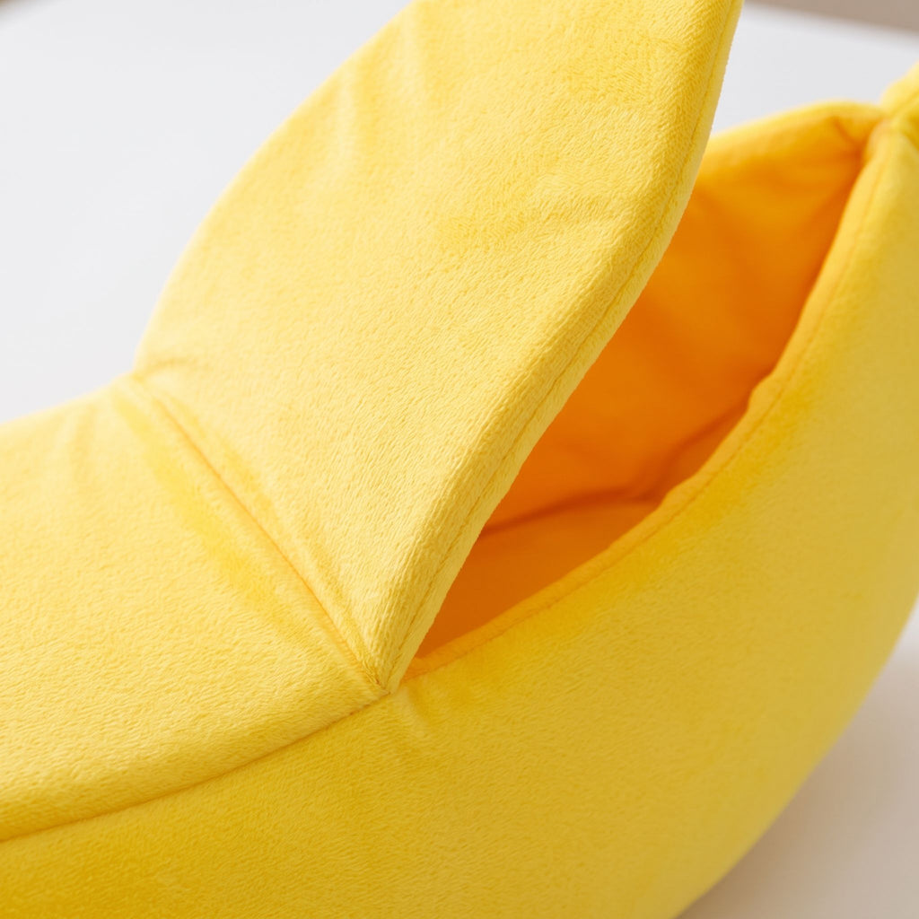 Detailed macro shot of the banana pet bed's peel-back flap showing velvet texture and stitching, white background.