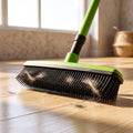 Close-up of pet hair removal broom mop with rubber bristles attracting pet fur on a wooden floor under sunlight.