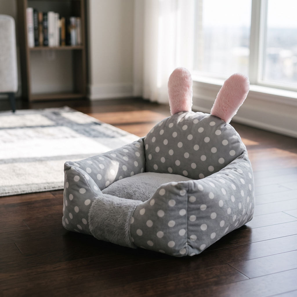 Close-up of plush dog bed with bunny-ear detail, showing soft fabric texture and polka-dot pattern in a modern living room.